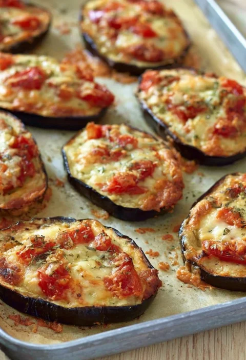 Pizzette di melanzane con pomodorini freschi e mozzarella filante.