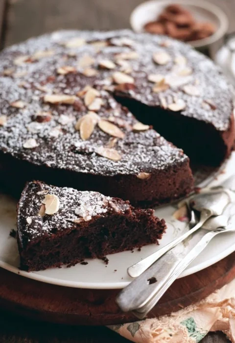 Fetta di Torta Umida al Cioccolato Fondente e Mandorle su un piatto elegante.