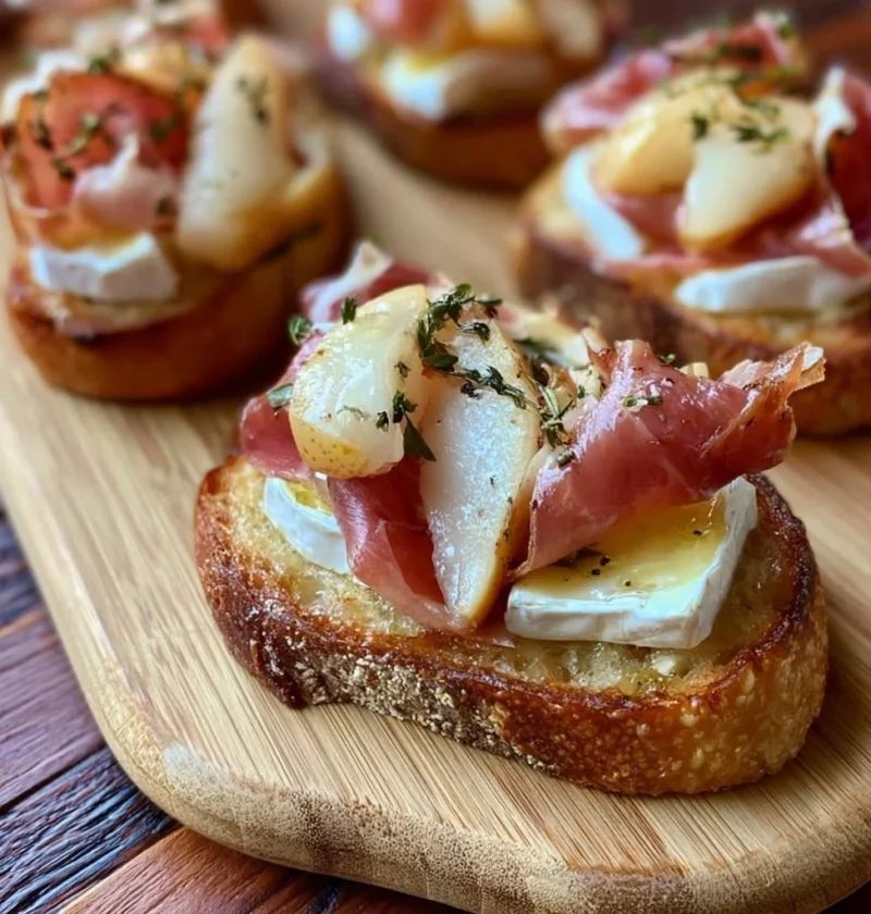 Crostini con brie, pere e prosciutto crudo serviti su un vassoio elegante