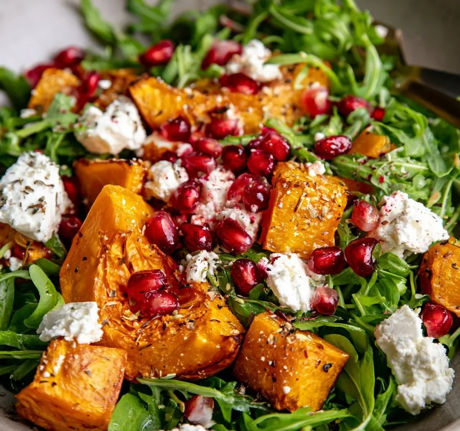 Insalata di zucca arrostita con feta e melograno in un piatto elegante.