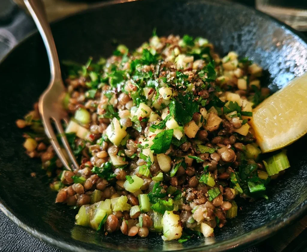 Insalata di lenticchie, mela e sedano pronta da servire in un piatto colorato.