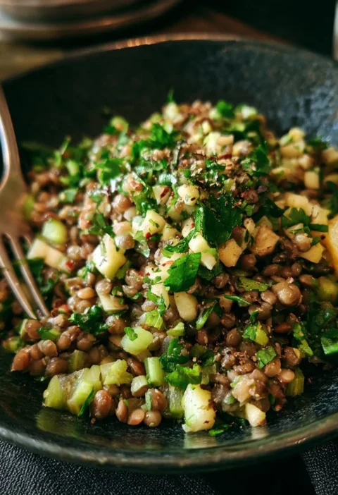 Insalata di lenticchie, mela e sedano pronta da servire in un piatto colorato.