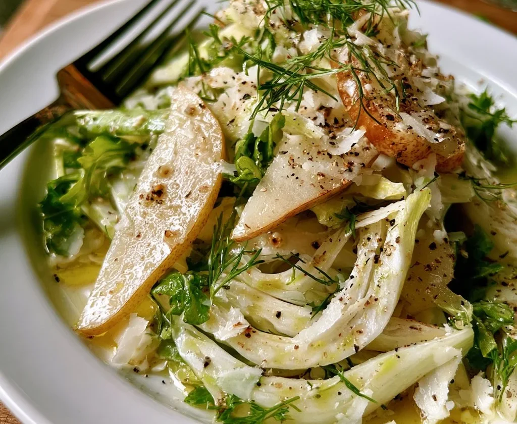Insalata di pere, finocchi e parmigiano servita in un piatto elegante