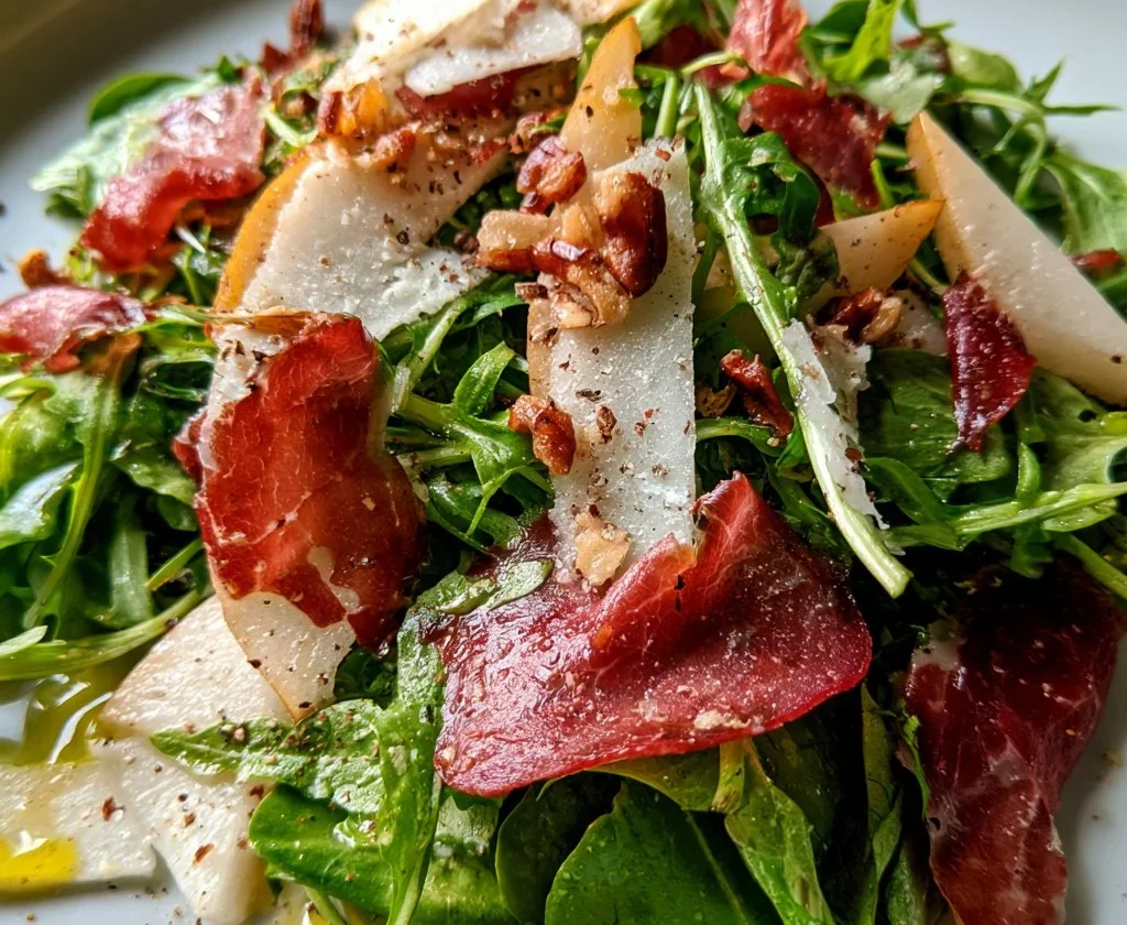 Insalata di rucola con pere, bresaola e grana su un piatto elegante