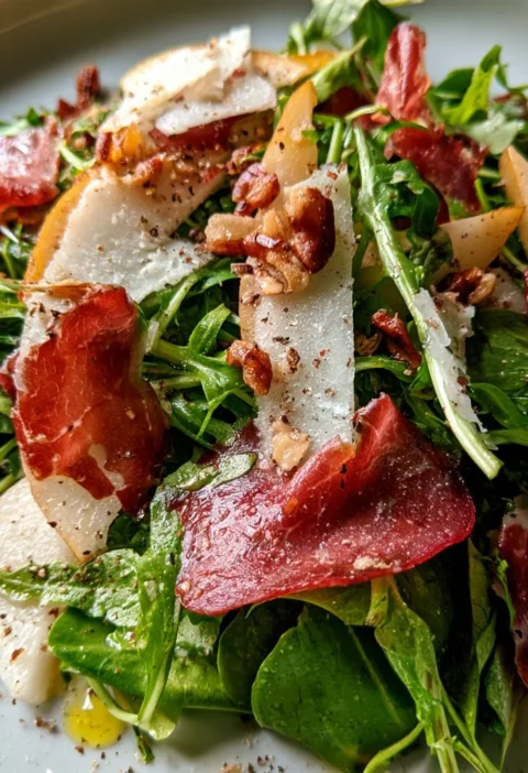 Insalata di rucola con pere, bresaola e grana su un piatto elegante
