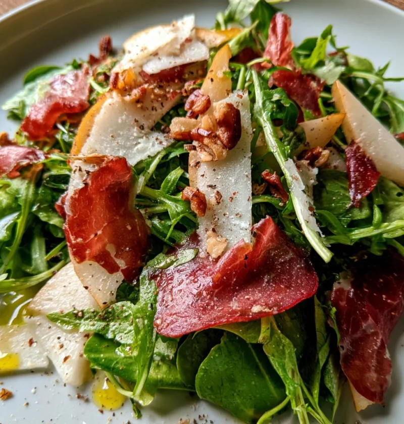 Insalata di rucola con pere, bresaola e grana su un piatto elegante